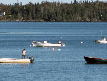 One fishermen uses a skiff to tow a skiff with another fisherman in the Fox Islands Thorofare. 