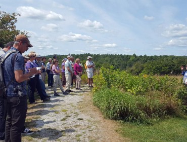 Conference attendees at Whaleback Shell Midden Historic Site in Damariscotta listen to Arthur Spiess, a senior archaeologist with Maine Historic Preservation. 