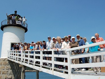 Members of two island lighthouse committees pose on the walkway of the Isle au Haut light.