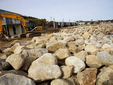 An excavator works to repair a seawall at Popham Beach.