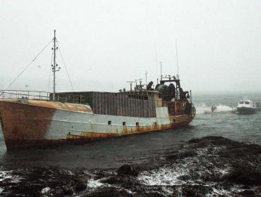 Fishing boat on rocks.