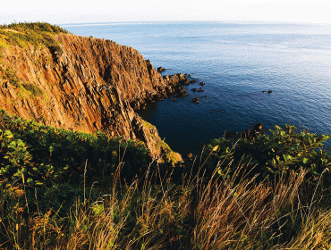 The setting sun illuminates rocks on the island's western shore.