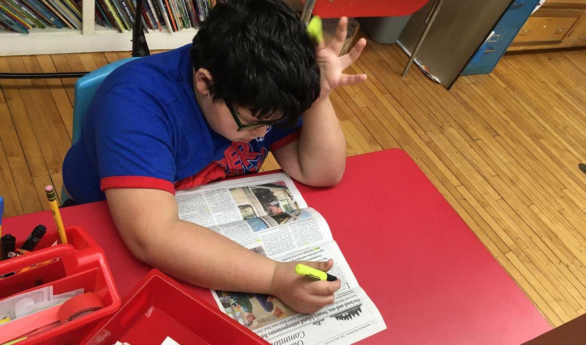 Wyatt, a student on the Cranberry Isles, uses the newspaper to highlight words with the "ch" and "th" sounds.