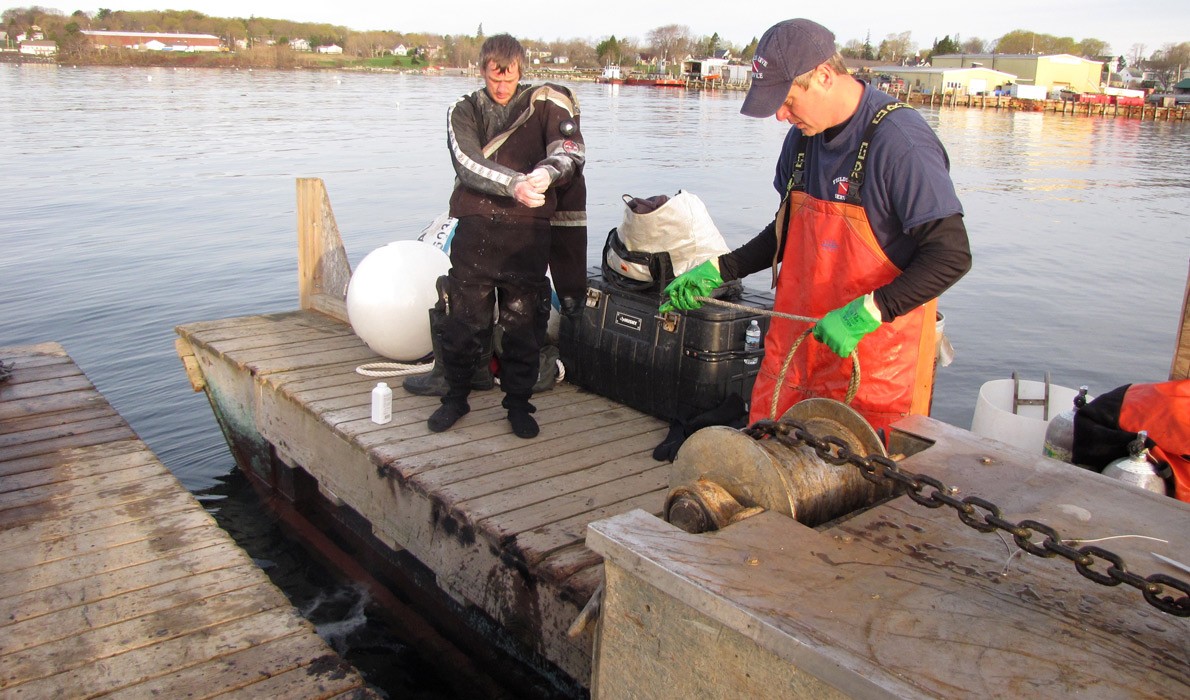 Lucas Fields, left, dons a dry suit as Dallas Fields prepares a chain.