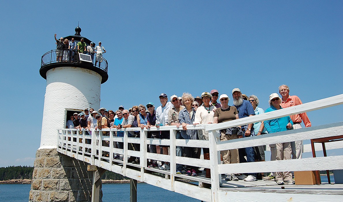 Members of two island lighthouse committees pose on the walkway of the Isle au Haut light.