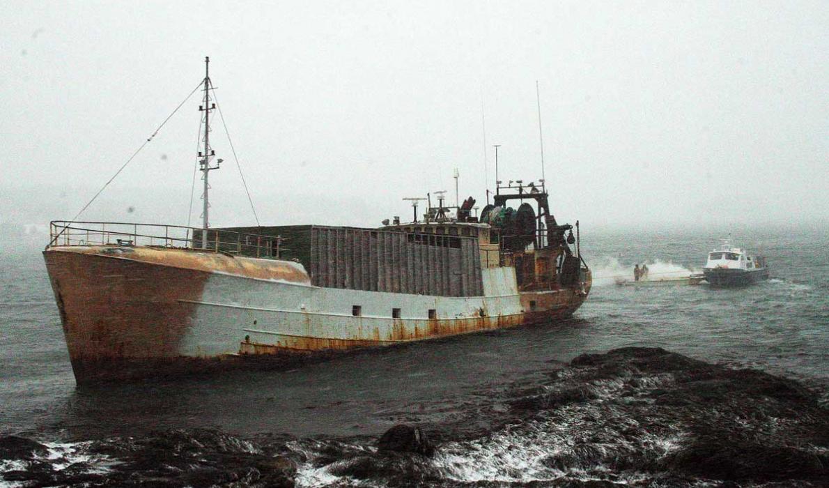 Fishing boat on rocks.