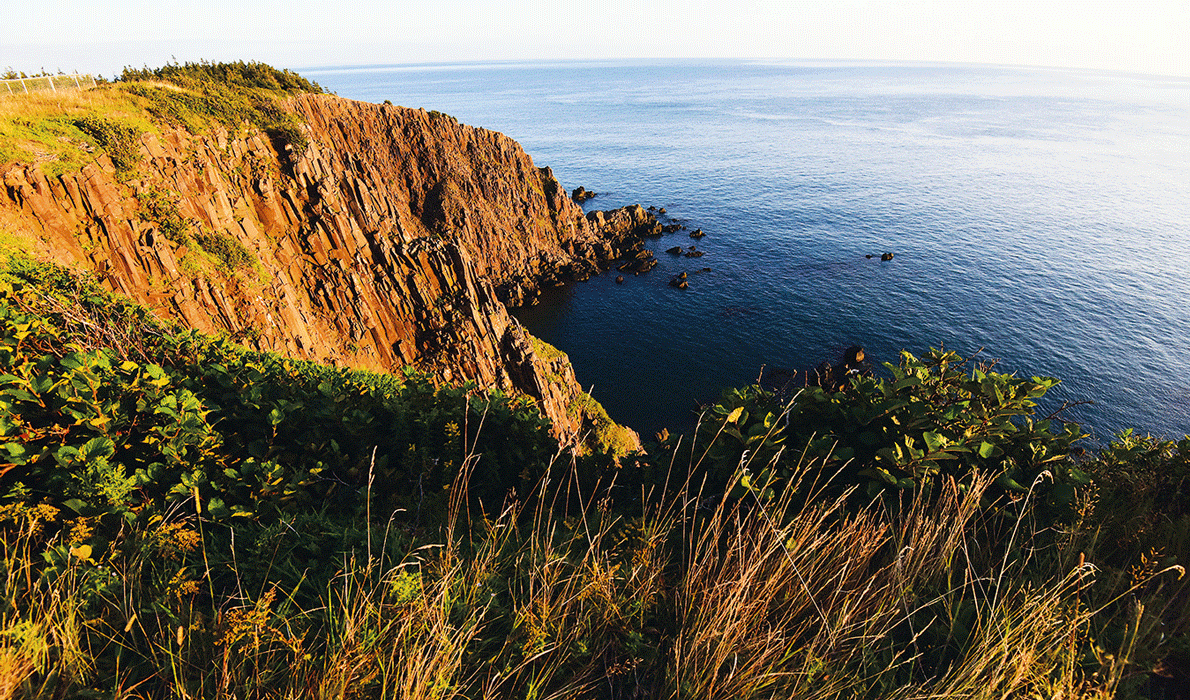 The setting sun illuminates rocks on the island's western shore.