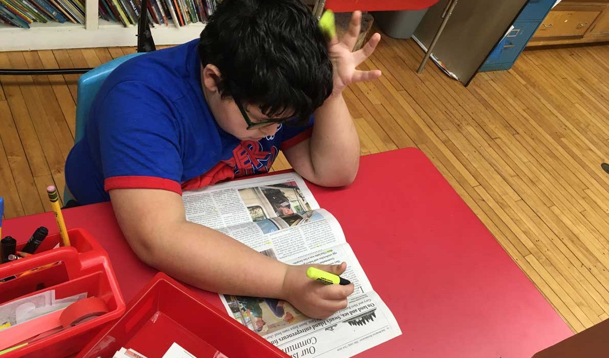 Wyatt, a student on the Cranberry Isles, uses the newspaper to highlight words with the "ch" and "th" sounds.